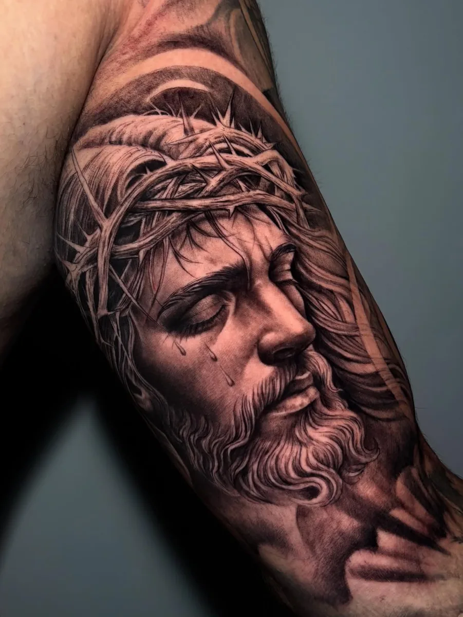 Cristo com coroa de espinhos em realismo no braco